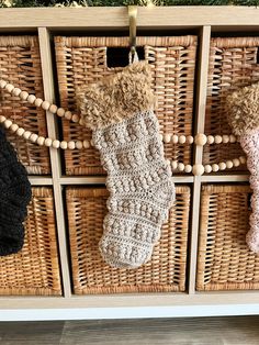 three crocheted mitts hanging from pegs in front of wicker baskets