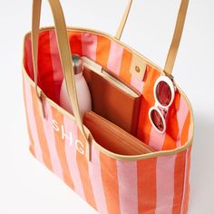 A beautiful bag, whether you're bound for the beach or brunch. Crafted from canvas featuring classic cabana stripes in vibrant pink and orange with a magnetic closure and vegan leather piping and handles. Add a monogram to put your own touch on the design or to make a memorable gift.    19"w (top), 15"w (bottom) x 5"d x 12"h  Canvas; polyester lining; vegan leather.  Spot clean with a damp cloth.  Imported.  Monogramming is embroidered. Trendy Pink Canvas Bag With Double Handle, Pink Canvas Bag With Leather Handles, High-end Monogram Canvas Bag For Everyday, High-end Monogram Canvas Bags With Handles, Multicolor Rectangular Monogram Canvas Bag, Tropical Luxury, Boat Tote, Banana Leaf Print, Shell Print