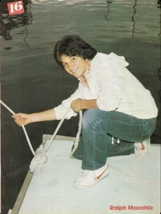 a young man sitting on top of a boat in the water