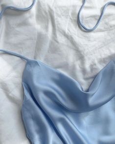 a blue dress laying on top of a white sheet