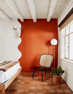 a bedroom with an orange accent wall and white ceiling, along with a chair in the corner