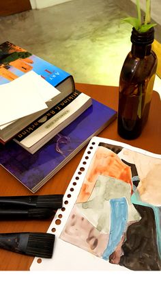 a wooden table topped with books and art supplies