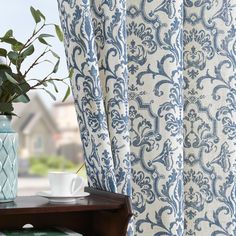 a blue and white vase sitting on top of a wooden table next to a window