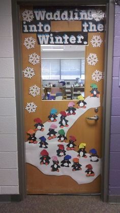 a bulletin board with penguins and snowflakes on the front door to a classroom