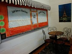 a restaurant with tables and chairs in front of the eiffel tower painting on the wall