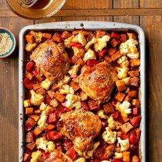 a casserole dish with chicken, potatoes and carrots in it on a wooden table