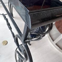 a metal bench sitting on top of a white floor next to a table with a clock