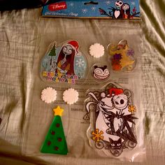 various stickers and magnets on a bed with a christmas tree in the background