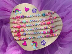 a wooden heart with lots of beads and charms attached to it on a purple tulle