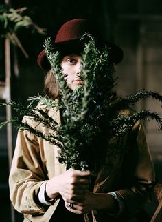 a man in a hat is holding some plants