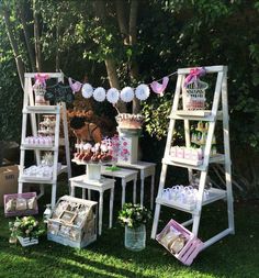 an outdoor party with white ladders and pink decorations on the grass, including cake