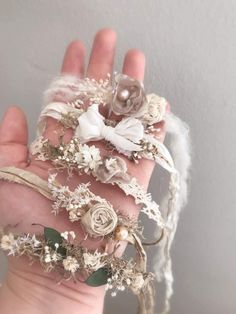 the hand is holding several pieces of fabric and flowers on it's fingers,