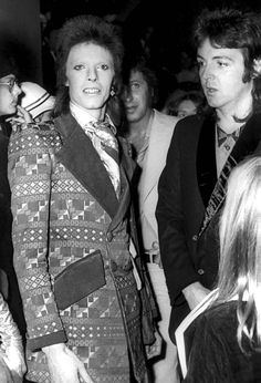 an old photo of a woman in a suit and tie standing next to other people