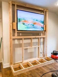 a flat screen tv mounted to the side of a wall in a room with hard wood flooring