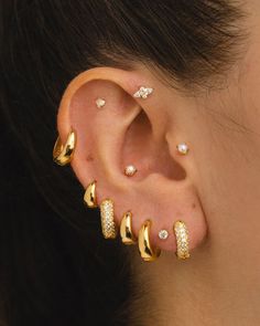 a close up of a person wearing gold ear piercings with diamonds on their ears