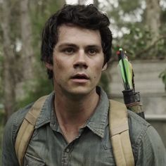 a young man holding an arrow in his hand while wearing a green shirt and backpack