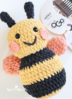 a crocheted stuffed bee sitting on top of a table next to a clock