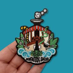 someone is holding up a small patch with an adventure ahead design on the front and back