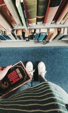 someone is sitting on the floor with their feet up in front of bookshelves