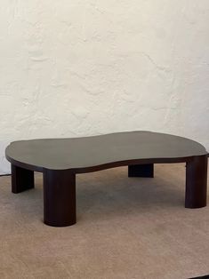 an oval shaped table sitting on top of a carpeted floor next to a white wall