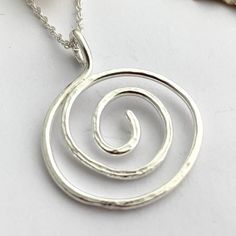 This elegant and modern hand forged wire sterling silver spiral pendant features a hammered texture and has been highly polished to a lovely shiny finish. The 2.6 cm pendant hangs from a bail which forms part of the pendant and a pretty 18 inch / 45 cm sterling silver chain which closes with a bolt clasp. Other chain lengths available - see below. This pendant is perfect for any occasion and an ideal birthday or anniversary gift for someone special. Or even a treat for yourself! I created the pe Spiral Hammered Jewelry As Gift, Spiral Hammered Jewelry Gift, Spiral Silver Jewelry For Anniversary, Silver Spiral Jewelry For Anniversary, Minimalist Silver Spiral Necklace, Modern Twist Silver Hammered Jewelry, Silver Spiral Necklace For Anniversary, Hand Forged Spiral Jewelry For Anniversary, Hand Forged Silver Swirl Jewelry