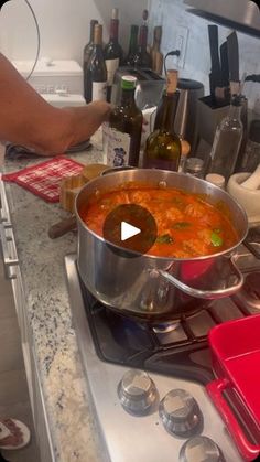 a person is cooking in a pot on the stove with wine bottles and other kitchen items