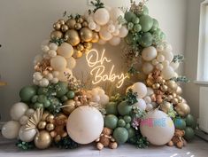 an arch made out of balloons and greenery with the words oh baby on it