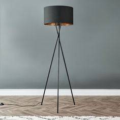 a floor lamp with a black shade on the top and a white rug underneath it