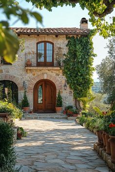 a stone house with potted plants on the front and walkway leading up to it