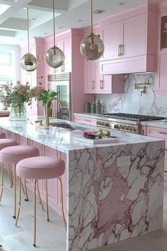 a pink kitchen with marble counter tops and stools