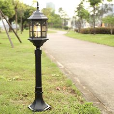 a black lamp post sitting on top of a grass covered field next to a sidewalk