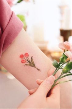 a woman holding flowers on her arm with the word love written in red and green ink