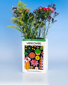 a vase with flowers in it sitting on a table next to a blue background and the words wildflowers