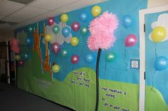 a bulletin board with balloons and streamers on the wall in an office hallway area