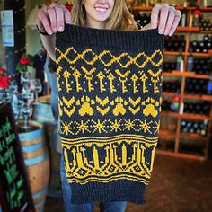 a woman holding up a knitted black and yellow sweater