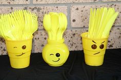 three yellow plastic cups with faces drawn on them