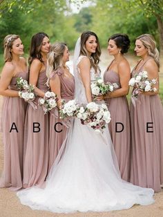 a group of women standing next to each other wearing dresses and holding bouquets in their hands