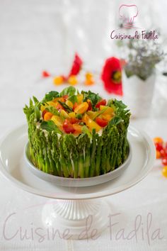 a cake decorated with asparagus and oranges on a white platter next to flowers