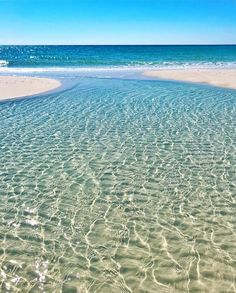 the water is very clear and blue with waves coming in from the shore on the beach