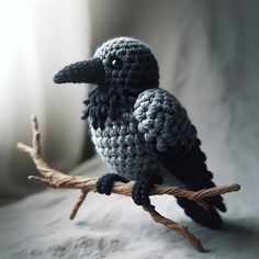 a crocheted bird sitting on top of a branch