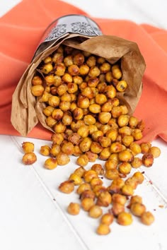 a bag filled with chickpeas sitting on top of a white table next to an orange cloth