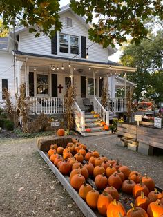 pumpkins are arranged in front of a white house with porches and lights on