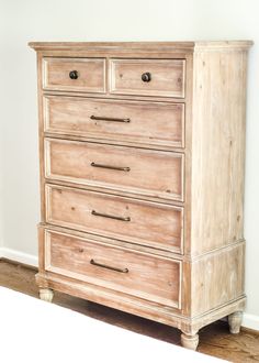 a wooden dresser sitting on top of a hard wood floor next to a white wall