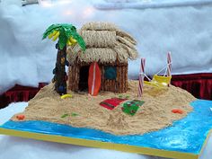 a cake made to look like a beach hut with palm trees on the sand and water