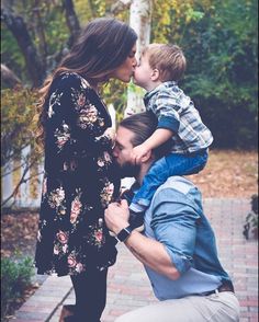 a man kissing a woman while holding a small boy in his lap and kissing her cheek