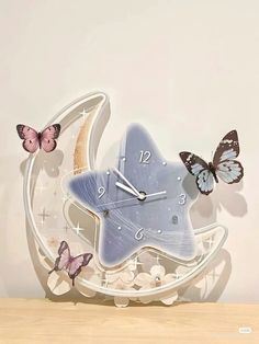 a clock with butterflies on it sitting on a table next to a wall mounted clock