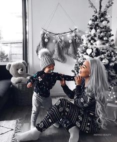 a woman and child sitting in front of a christmas tree