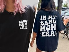 "✦ 🇺🇸SENT TO PRODUCTION AND PRINTED IN THE US🇺🇸 ✦The perfect In My Band Mom Era Graphic TShirt is yours!  ✦ QUICK FACTS ✦ Comfort Colors® C1717 T-Shirt is 100% ringspun cotton (ringspun=comfort) Preshrunk, soft washed, garment-dyed fabric Twill-taped back neck and shoulders ✦ SIZING TIPS ✦ All our garments are UNISEX.  FOR AN OVERSIZED LOOK, SIZE UP 2-3 SIZES For a Relaxed Fit order your Usual Size For a Snug Fit order 1 Size down If you're unsure: Lay your favorite fitting T-Shirt flat and *measure armpit to armpit (1\" under armpit) for width *measure from point where neck seam meets shoulder all the way to bottom for length & compare with measurements in Size Chart provided in each listing *Please note, Size Chart Measurements are to be used as guidelines and measurements may vary w Band Merch Shirt With Slogan For Fans, Band Merch Shirt With Slogan For Concerts, Band Merch Slogan Shirt For Fans, Band Merch Shirt With Slogan, Band Merch Shirt With Text Print For Concert, Cotton Slogan Shirt For Concert, Band Mom Shirts, Band Mom, Mom Era