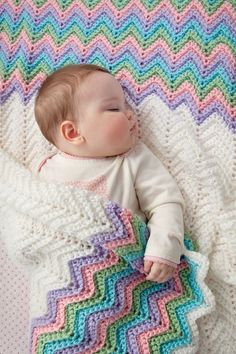 a baby laying on top of a colorful blanket