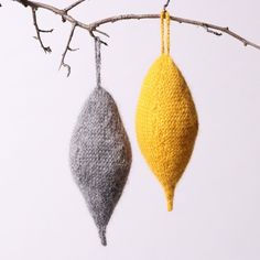 two knitted ornaments hanging from a tree branch